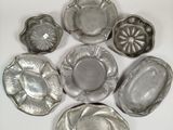 several silver metal dishes are arranged in a circle on a white surface