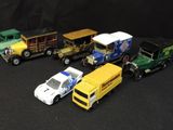 five toy cars and a truck on a black surface