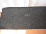 someone is writing on a piece of black paper on a wooden table