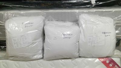 three bags of white pillows sitting on top of each other