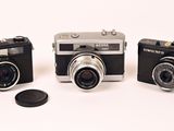 three cameras sitting next to each other on a white surface