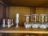 many wine glasses sitting on a shelf in a cabinet