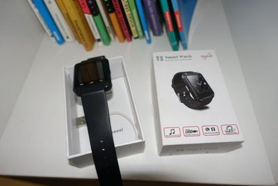 a black smart watch sitting next to a box of pens
