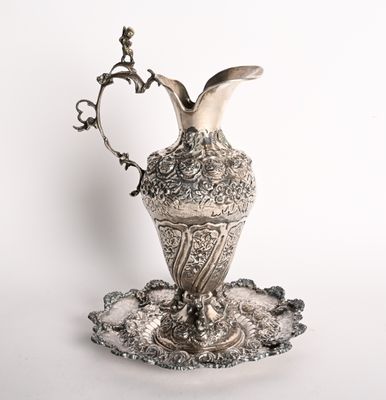 un plateau ancien en argent sur lequel est posé un vase en argent, le tout sur un fond blanc