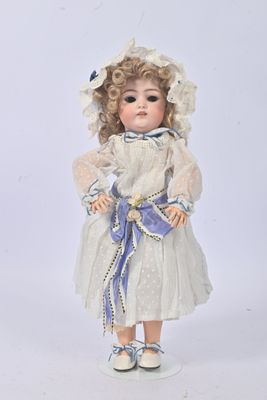 poupée en porcelaine représentant une petite fille vêtue d'une robe blanche et d'un chapeau