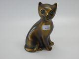 un petit chat en bronze avec une médaille attachée à son collier