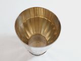 a silver cup with a handle on a white surface
