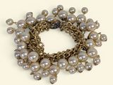 bracelet orné de perles et de chaînes en or sur fond blanc