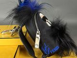 black bag with blue and black feathers on it sitting on top of a yellow table