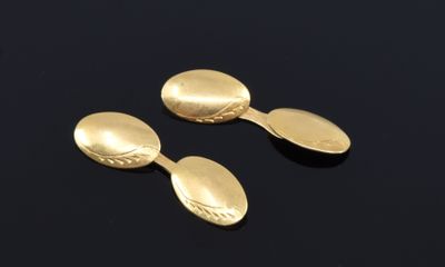 two gold spoons and a spoon rest on a black surface