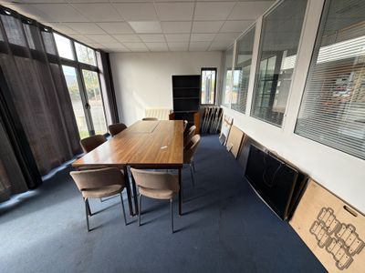 une longue table avec des chaises dans une pièce dotée de nombreuses fenêtres