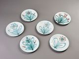 six small plates with flowers painted on them on a table