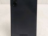 a close up of a black samsung phone on a white surface