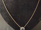 a gold necklace with a blue and white diamond pendant on a mannequin
