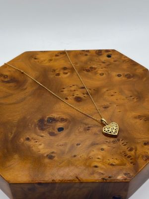 une image représentant une boîte en bois sur laquelle est posé un collier en or