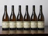 six bouteilles de vin sont alignées sur une table en bois