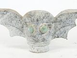 a small statue of a bat with green eyes on it