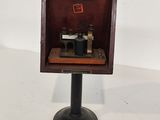un microscope à l'ancienne, dans un coffret en bois posé sur un socle métallique
