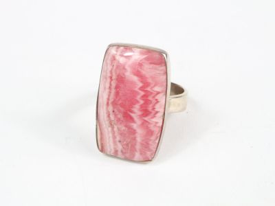 gros plan d'une bague en pierre rose sur une surface blanche