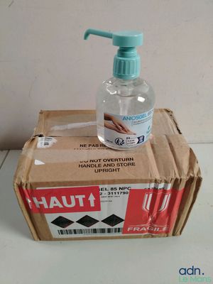 un flacon de gel hydroalcoolique posé sur une boîte