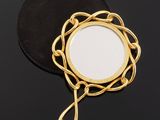 a close up of a mirror on a black surface with a chain around it