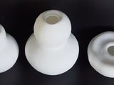 three white vases sitting on a table with a black background