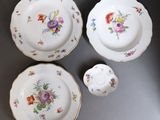 quatre pièces de vaisselle en porcelaine ornées de fleurs, posées sur une table