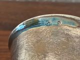 a close up of a silver cup on a wooden table