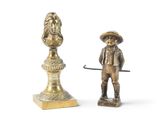 figurine en laiton représentant un homme avec un chapeau et une canne, à côté d'un buste d'un homme avec un chapeau et une canne