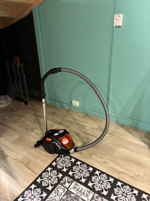 un tapis noir et blanc posé par terre à côté d'un aspirateur