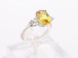 a close up of a yellow sapphire and diamond ring on a clear stand