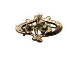 an image of a gold broochle with flowers and leaves