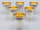 six verres à shot argentés aux bords dorés sur fond blanc