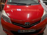 the red toyota yaris is parked in a garage with other cars in the background