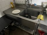 un évier dans une petite cuisine, avec de la vaisselle posée sur le plan de travail