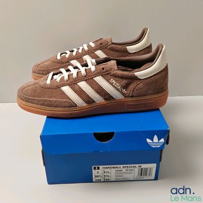 des baskets Adidas marron et blanches posées sur une boîte bleue