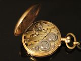 a gold pocket watch with a chain on a black surface