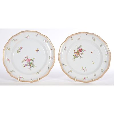 two plates with floral designs on them sitting on a white surface