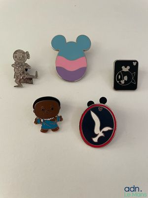 three disney pins are sitting on a white surface