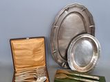 trois assiettes et cuillères en argent plaqué dans un coffret en bois posé sur une table