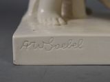 a white figurine of a woman sitting on a book