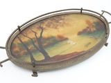 an oval tray with a painting of a landscape on it