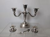 a silver candelab with three candles on a clear table