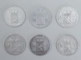 six different british coins are arranged in a row on a white surface