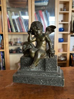 une statue représentant un petit ange assis sur une table