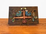 une photo d'une plaque en bois sur laquelle figurent un oiseau et des fleurs