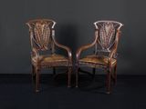 une paire de chaises anciennes aux assises recouvertes de cuir, posées devant un mur noir