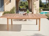 une table en bois sur une terrasse, avec un verre de vin posé dessus
