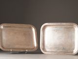 two silver trays sitting on top of a table next to each other
