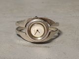 une bague en argent ornée d'une horloge, posée sur une table